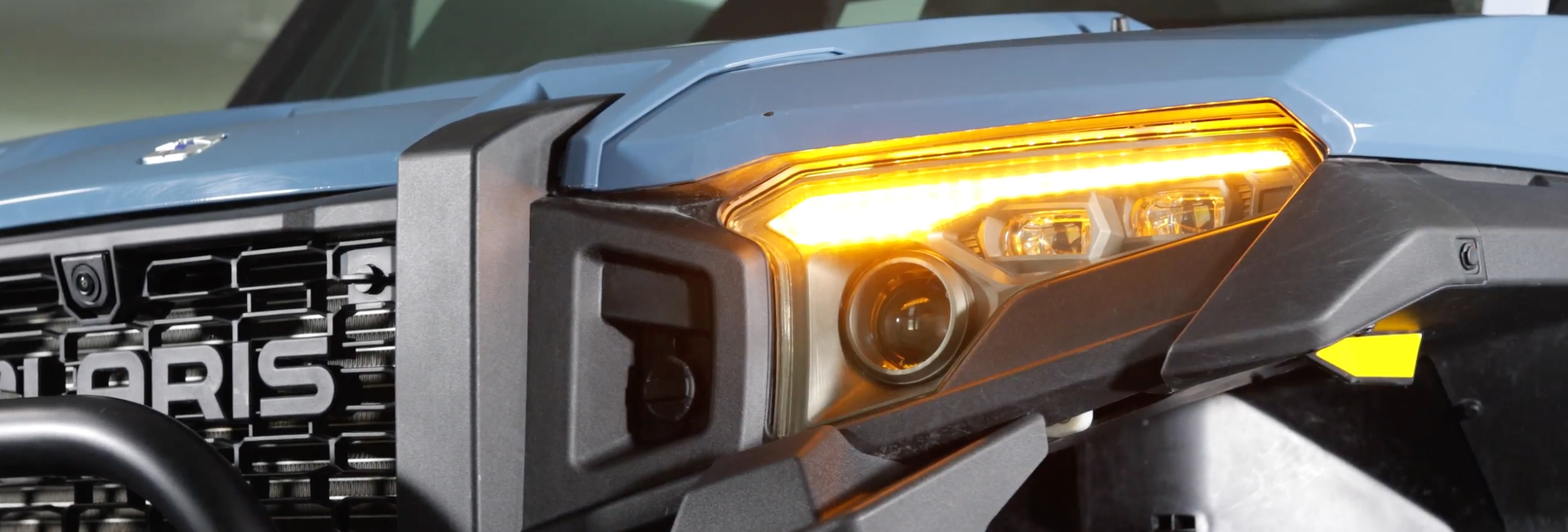 Close-up of a Polaris Xpedition headlight with integrated turn signal, showcasing the design detail and yellow turn signal.